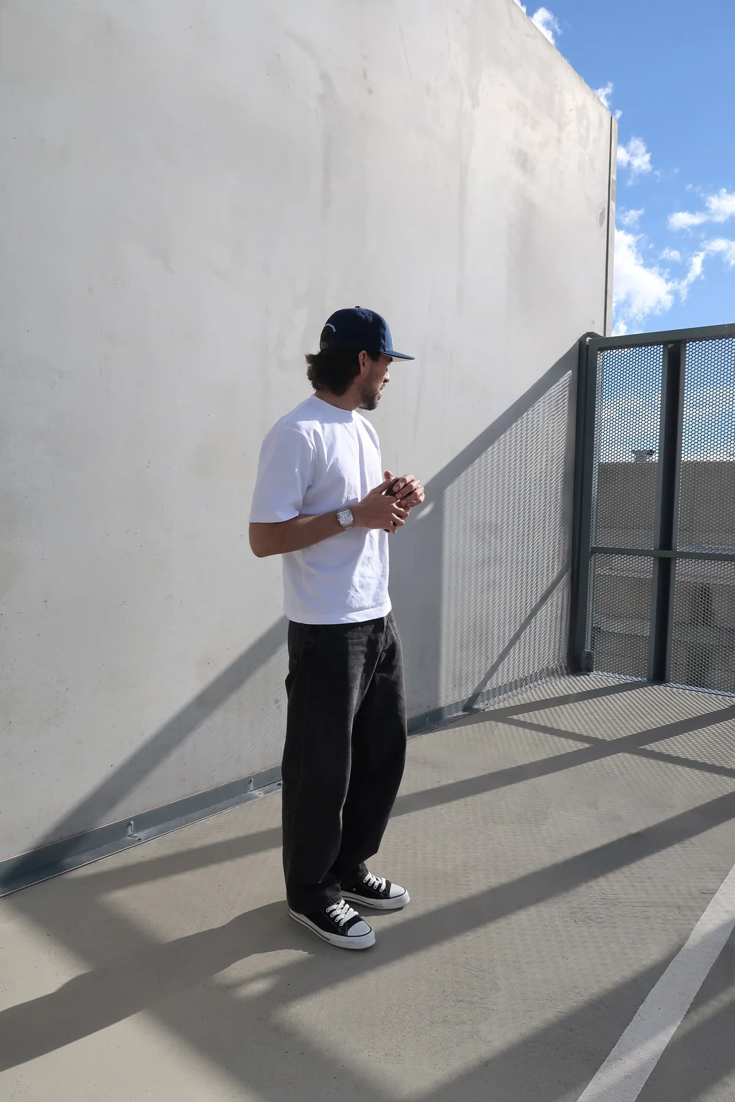 The navy cap with a complete daylight outfit beside a concrete wall.